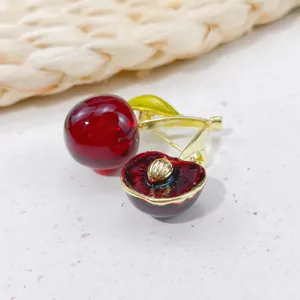 Macro view of a cute cherry brooch featuring realistic red resin and gold-tone details