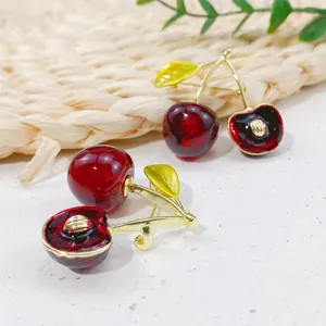 Detail showing the exquisite texture of red cherry brooches with golden leaves.