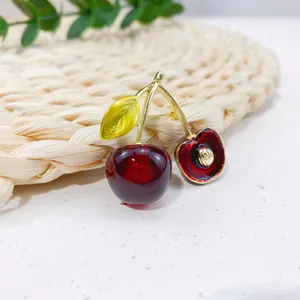Close-up of a cute cherry brooch with detailed red resin fruit and golden leaves