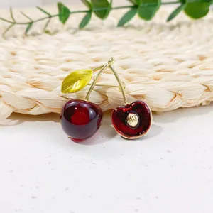 Detailed close-up view of a cute red cherry brooch pin with realistic gold leaf accents