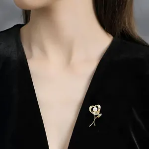 Detailed view of an elegant golden rose brooch with pearl and crystal on black velvet