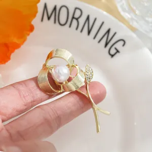 Detailed view of a gold rose flower brooch featuring a pearl and rhinestone accents