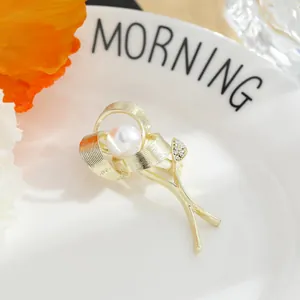 Detail view of elegant gold rose flower brooch with central pearl and crystal accents