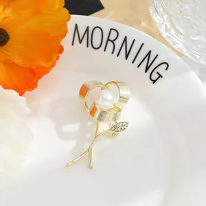 Elegant detail showing a gold rose brooch with central pearl and sparkling leaf
