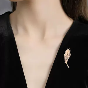Close-up of an elegant gold wheat ear brooch with cat's eye stones on black dress