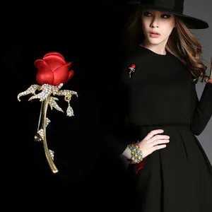 Detailed view of an elegant red rose brooch with crystals and teardrop pendant