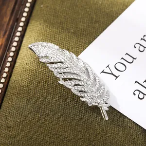 Macro detail of an elegant silver feather brooch with sparkling rhinestone inlay