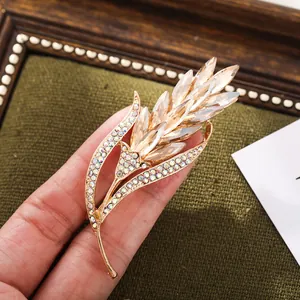 Close-up of a champagne gold wheat ear brooch with sparkling rhinestones and crystals.