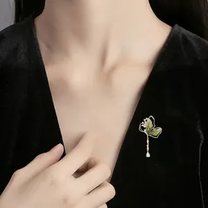 Eleganter grüner Schmetterlingsbrosche mit Quaste auf einem schwarzen Samtkleid Details