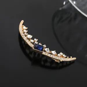 Elegant crescent moon brooch with a large rectangular blue gemstone and crystals.