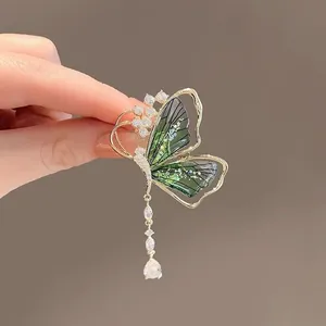 Detailaufnahme einer grünen Schmetterlingsbrosche mit glänzenden Kristallquasten