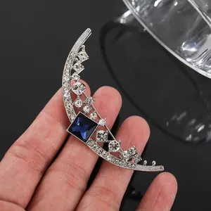 Detail showing silver moon brooch with blue sapphire-like gemstone and rhinestones