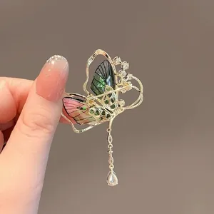 Detailansicht einer Schmetterlingsbrosche mit grünen Flügeln und elegantem Quastenanhänger