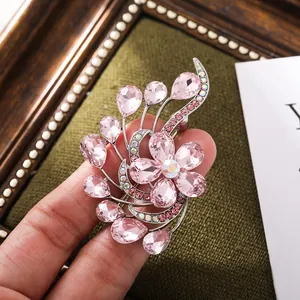 Detailed close-up of an elegant pink crystal floral brooch held by hand for scale