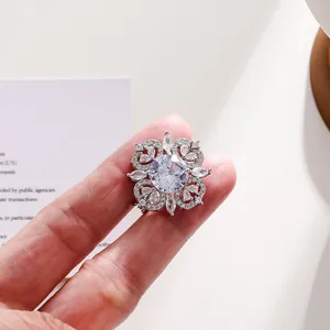Detailed macro view of a vintage silver-toned floral crystal brooch held by hand.