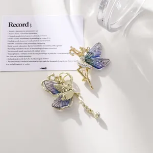 Vista detallada de broches translúcidos de mariposa y hada con detalles en oro y borlas