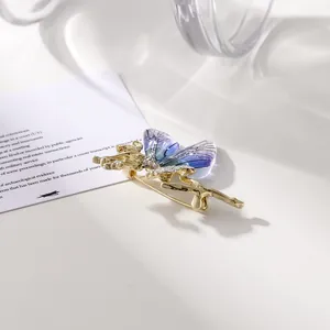 Macro de un broche de mariposa dorado con alas púrpuras translúcidas y cristales