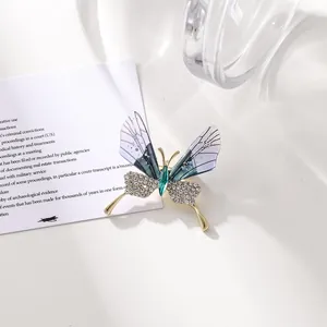 Primer plano de un elegante broche de mariposa con alas translúcidas y pedrería brillante