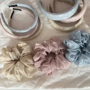 Detail shot of floral hair scrunchies and headbands in pastel blue, pink, and yellow.