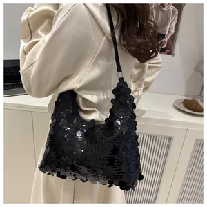 Sac à main hobo à paillettes noires élégant porté par un modèle dans un décor intérieur