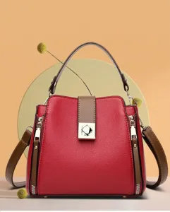 Bolso bombonera de cuero rojo texturizado con asas marrones y hebilla dorada.