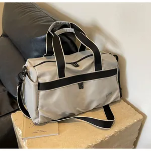 Side view of grey oxford travel bag on stone block with black reinforced handles.