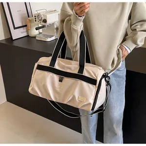 A person holding a large beige oxford travel bag in a stylish minimalist setting