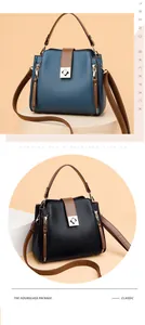 Juego de elegantes bolsos tipo cubo en azul y negro con asas marrones y cierres dorados.