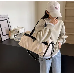 Lifestyle view of a large beige Oxford cloth travel tote bag with black straps.