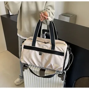Close-up of lightweight cream Oxford cloth travel tote bag held over white suitcase