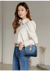 Modelo mostrando un bolso de cubo de cuero azul premium con elegantes detalles dorados