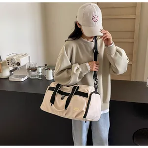 Asian model wearing a large beige Oxford cloth travel bag in a modern cafe setting