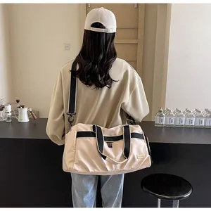 Back view of a woman carrying a large beige oxford travel tote bag in a minimalist cafe