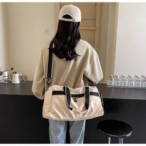 Back view of a model carrying a beige large capacity Oxford cloth travel bag in a cafe