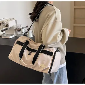 Detail view of a large beige Oxford cloth travel bag with black straps carried by a woman