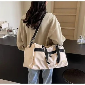 Detailed view of the large capacity cream Oxford cloth travel tote bag worn as a shoulder bag