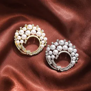 Close-up of gold and silver pearl brooches with rhinestones on brown satin background.