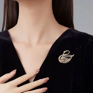 Detailed close-up of a golden swan brooch with rhinestones on black velvet garment