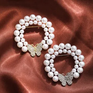 Detailed view of two elegant pearl brooches with rhinestone butterflies on brown satin.
