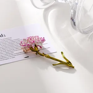 Macro view of an elegant purple enamel carnation flower brooch on a white surface