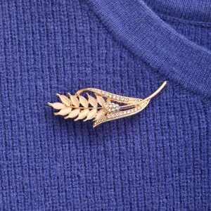 Macro view of elegant opal wheat ear brooch with rhinestones on blue knitted sweater.