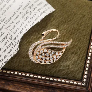 Detail of an elegant gold alloy swan brooch encrusted with sparkling white rhinestones