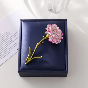 Elegant pink and white enamel carnation flower brooch with gold stem on navy jewelry box