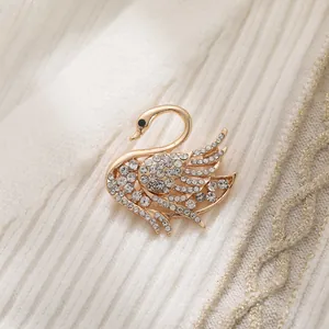 Close-up of elegant gold swan brooch encrusted with sparkling clear rhinestones on fabric