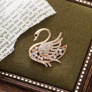 Close-up detail of an elegant gold swan brooch encrusted with sparkling rhinestones.