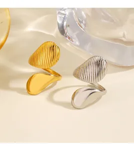 Detalle de anillos asimétricos oro y plata con textura estriada y acabado pulido.