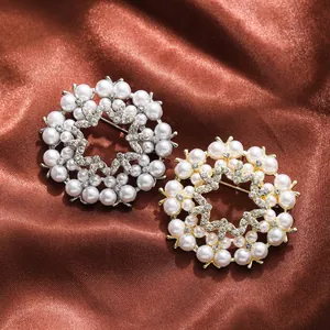 Close-up of elegant gold and silver floral brooches with pearls and rhinestones on satin.