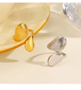 Detalle de anillos asimétricos gota de agua en oro y plata con textura