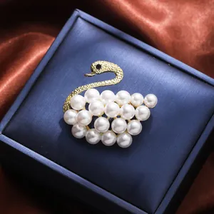 Elegant swan shaped brooch featuring white pearls and gold plating on navy blue box