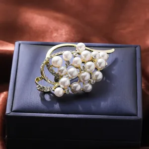 Detailed view of elegant gold floral pearl brooch with sparkling rhinestone leaf design